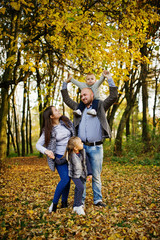 Fototapeta premium Happy caucasian family of mom dad and little girl with boy at majestic autumn fall forest.