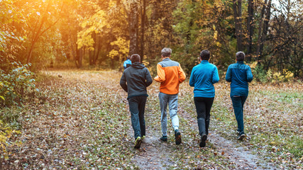 Running athletes in the park on a run in the early morning. Several children are running in the woods doing sports. Healthy lifestyle.