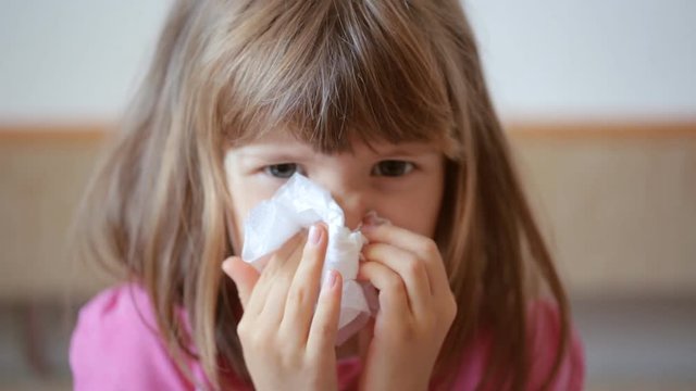 Little girl blowing her nose