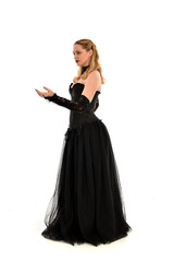 full length portrait of a blonde girl wearing black gothic gown. standing pose, isolated on white background.