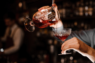 Male hands pouring a fresh alcoholic drink into the cocktail glass