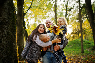 Fototapeta premium Happy caucasian family of mom dad and little girl with boy at majestic autumn fall forest.
