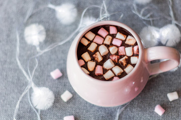 hot chocolate  pink ceramic mug marshmallows and garland  gray knitted background