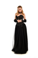 Naklejka premium full length portrait of a blonde girl wearing black gothic gown. standing pose, isolated on white background.