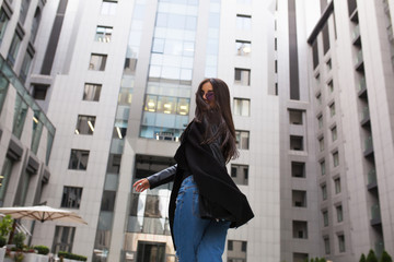 Fototapeta premium Pretty young model with hair blowing in the wind walking at the street