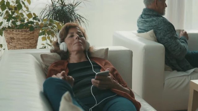 Senior couple with tablet and smartphone relaxing at home.