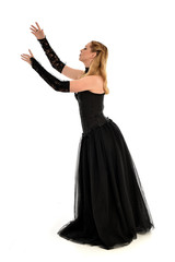Fototapeta premium full length portrait of a blonde girl wearing black gothic gown. standing pose, isolated on white background.