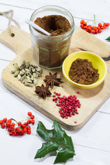 Gingerbread spices in the jar. White, wooden table. Wooden kitchen board.