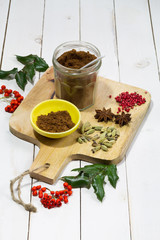 Gingerbread spices in the jar. White, wooden table. Wooden kitchen board.