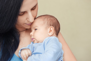 mother holding and kissing newborn baby