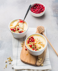 Classic cheesecake in small ceramic jars with fresh cranberries, nuts and honey on light concrete background and wooden board. The most delicious dessert or the perfect healthy breakfast!)