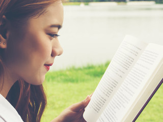 Fototapeta premium Close up face of young woman reading book at the park.