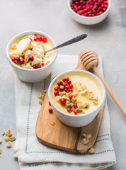 Classic cheesecake in small ceramic jars with fresh cranberries, nuts and honey on light concrete background and wooden board. The most delicious dessert or the perfect healthy breakfast!)