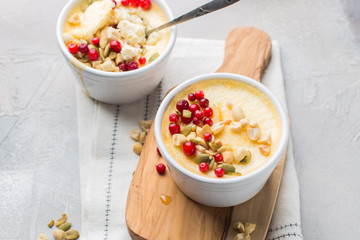 Classic cheesecake in small ceramic jars with fresh cranberries, nuts and honey on light concrete background and wooden board. The most delicious dessert or the perfect healthy breakfast!)