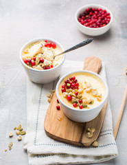 Classic cheesecake in small ceramic jars with fresh cranberries, nuts and honey on light concrete background and wooden board. The most delicious dessert or the perfect healthy breakfast!)