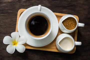 Hot cup of black coffee with white flower decor on table