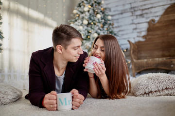 couple holding mugs against  christmas tree in room (1)