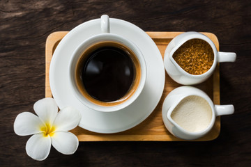 Hot cup of black coffee with white flower decor on table