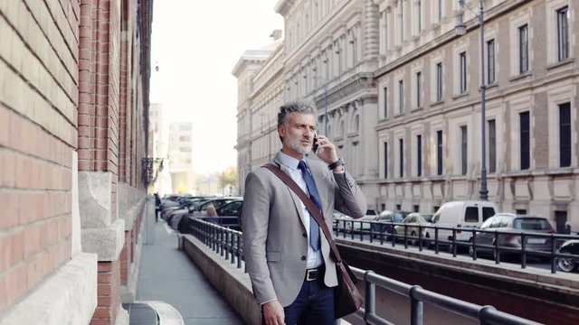 Mature businessman with a smartphone in a city.