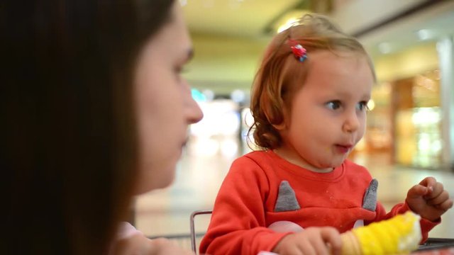 Little child girl eating an Ice Cream Gelato Sour Taste with Mom in Grocery Mall