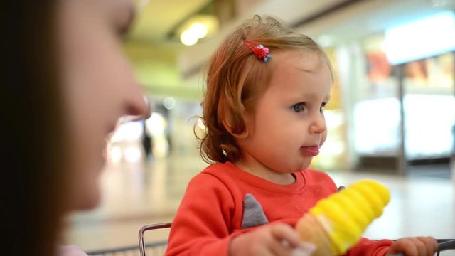 Little child girl eating an Ice Cream Gelato Sour Taste with Mom in Grocery Mall