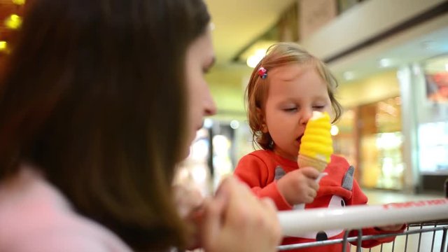 Little child girl eating an Ice Cream Gelato Sour Taste with Mom in Grocery Mall