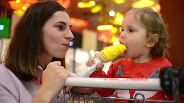 Little child girl eating an Ice Cream Gelato Sour Taste with Mom in Grocery Mall