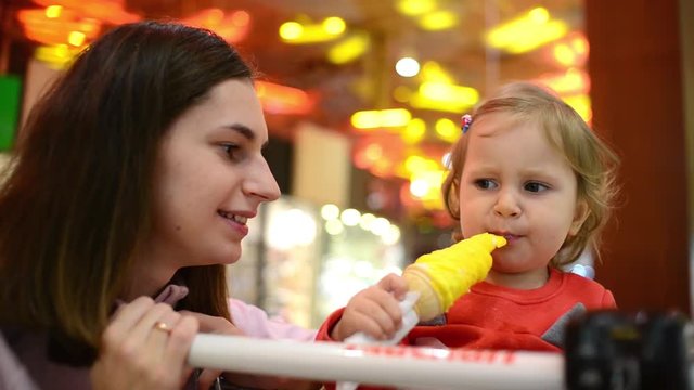 Little child girl eating an Ice Cream Gelato Sour Taste with Mom in Grocery Mall