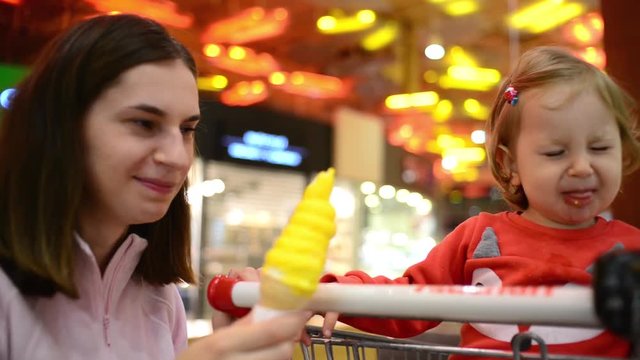 Little child girl eating an Ice Cream Gelato Sour Taste with Mom in Grocery Mall