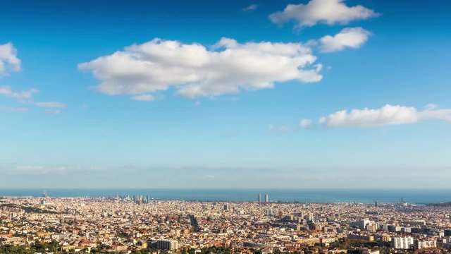 Panoramic view of Barcelona a sunny day. The great city with the sea of background and the clouds motion.Time Lapse