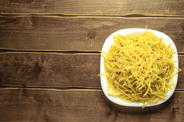 Dry pasta on a plate on a wooden background. A white plate. A series of snapshots of healthy nutrition.