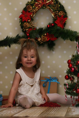 little girl sitting in front of a Christmas tree