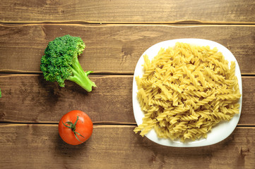 Dry pasta on a plate on a wooden background. A white plate. A series of snapshots of healthy nutrition.