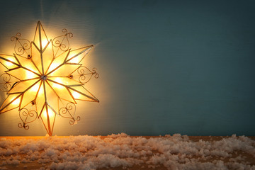 Image of christmas shining star over wooden background.