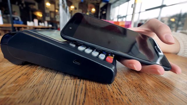 A close-up view of a POS NFC terminal in use. 