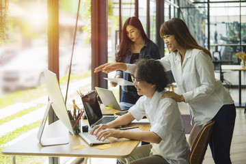 Creative business team discussing while working together new project in office. Team designers standing around the table and discussing new ideas while graphic man using digital tablet.