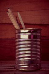 Pencils in a tin can on a wooden floor