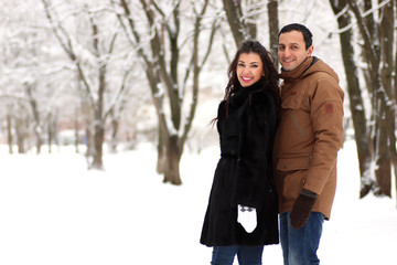 A young couple walk in a winter park