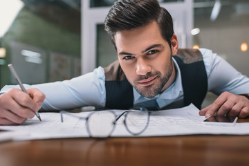 adult businessman working with blueprint in office