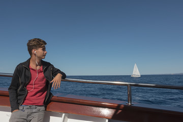 Fototapeta premium Teen boy listens to music in headphones and travels on the Adriatic Sea