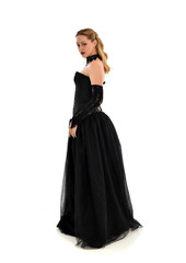 Naklejka premium full length portrait of a blonde girl wearing black gothic gown. standing pose, isolated on white background.
