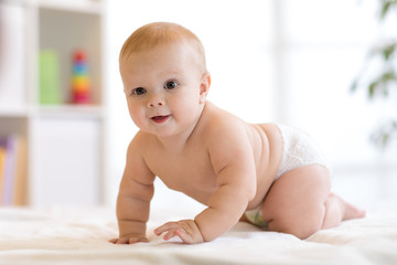 Portrait of a crawling baby on the bed in nursery room