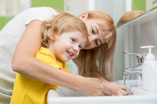 Mother and child son washing their hands in the bathroom. Care and concern for kids.