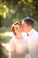 Fototapeta premium The bride and groom in the background of park trees