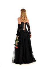 full length portrait of a blonde girl wearing black gothic gown. standing pose, isolated on white background.