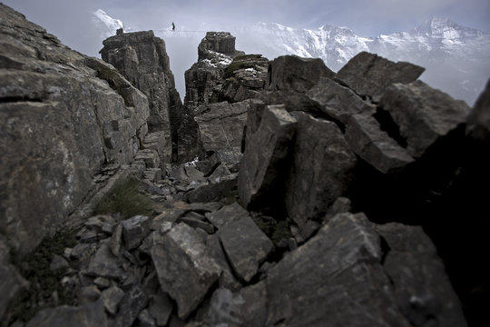 Person balancing on high line between two rocks Schilthorn, Switzerland