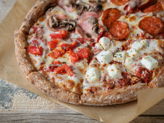 Homemade pizza set on paper at wooden table