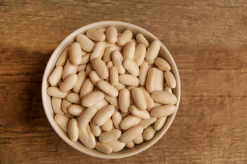 Big white kidney beans in the bowl on a wooden table