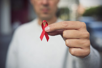 man with red ribbon for the fight against AIDS - obrazy, fototapety, plakaty