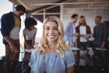 Smiling business woman with creative team in background